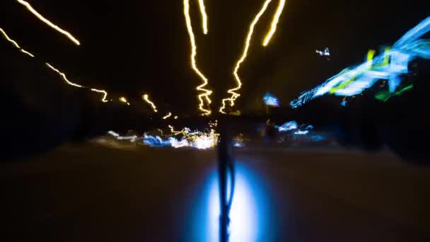 Aydınlanmış şehrin gece caddelerinde hızlı bir şekilde elektrikli scooter kullanan bir adam. — Stok video