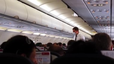 Oturan yolcular ve servis görevlileriyle birlikte uçuş için hazırlanan uçağın içine bakın.
