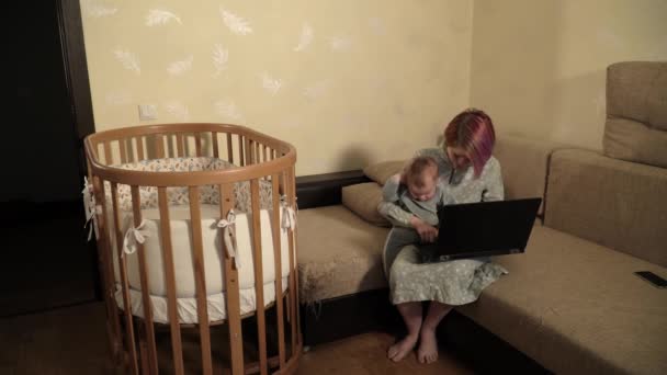 Mãe solteira está tentando trabalhar em casa com bebê de joelhos, mas ele está distraindo-a — Vídeo de Stock