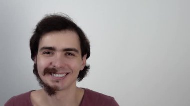 Genç adam yüzünü yüzünün arkasına saklar ve sakalının yarısı tıraşlı bir şekilde gösterir.