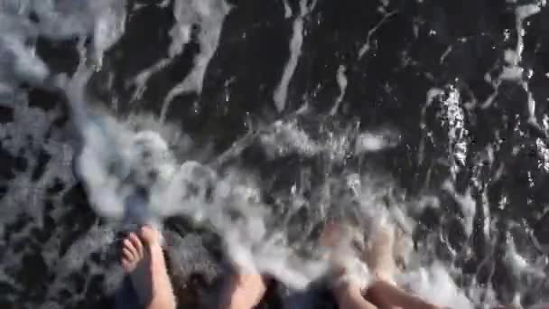 Ноги дві людини, омиті океанськими хвилями вид зверху — стокове відео