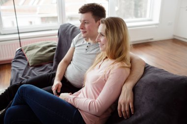 couple enjoying themselves and watching tv on the sofa