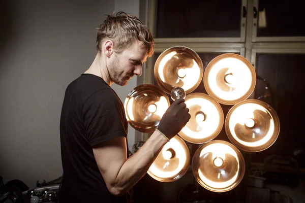 Light designer looking at electric bulb — Stock Photo, Image