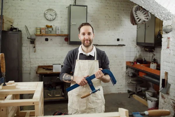 Carpinteiro está olhando e segurando uma braçadeira azul — Fotografia de Stock