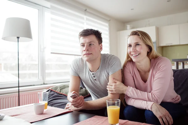 Couple enjoying themselves and watching tv on the sofa — ストック写真