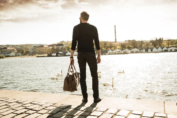 Onun çantası ile şık delikanlı Nehri önünde duruyor