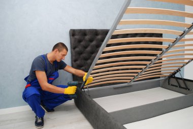 Usta, alıcının dairesinde kaldırma mekanizması olan yeni bir yatak kuruyor.