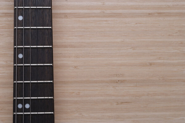 Electric guitar fretboard on a wooden background texture