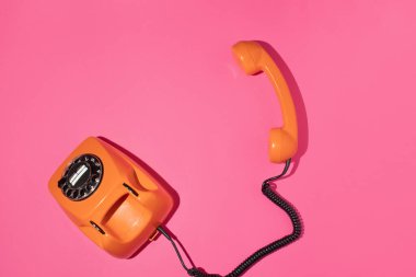 Pembe parlak arka planda eski bir telefon. Klasik estetik tarzı. Moda en düşük düzlük. Bahar ya da yaz güneşli cep telefonu fikri. Mutlu yaşam iletişimi kavramı.