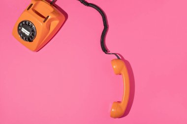 Pembe parlak arka planda eski bir telefon. Retro estetik stil. Moda en düşük düzlük. Bahar ya da yaz güneşli bir fikir. Eğlenceli cep telefonu iletişim konsepti.