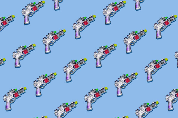 Creative pattern made with space gun toy on pastel blue background. Fun creative idea. Flat lay.