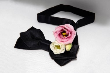 Beyaz arka planda farklı renkte östoma çiçeklerinden oluşan güzel bir buket siyah bir papyonun yanında.