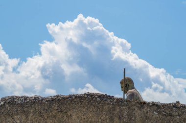 Pompeii 'ye bağışlanan Daedalus heykeltraşı Igor Mitoraj' ın bronz heykeli. Daedalus arka planda bulutlarla duvarın diğer tarafında..