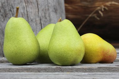 Eski bir tahta üzerinde dört yeşil armut.