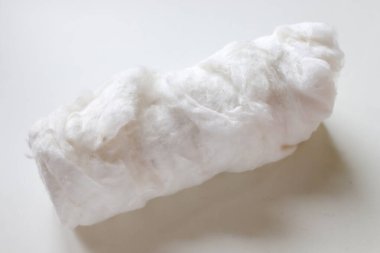 Beyaz arka planda beyaz pamuk rulosu. Seçici odak, yakın plan, kapalı alan.