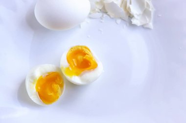 Haşlanmış yumurta soyuldu ve beyaz yumurta ve yumurta kabuğunun yanında ikiye bölündü. Beyaz bir yüzey üzerinde seçici bir odak noktasında.
