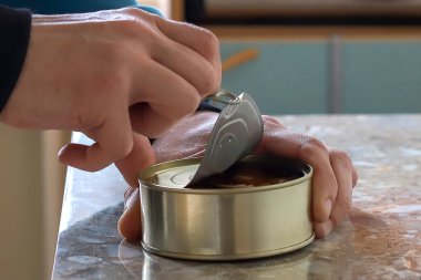 Adam içeride metal bir konserve kutusu açıyor.