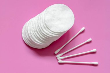 Temiz pamuk pedleri ve pamuk tomurcukları pembe arka planda. yüz ve vücut bakımı için ögeler