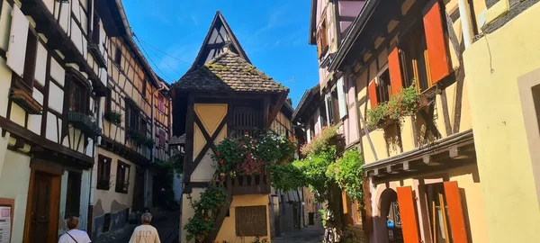 Turistler Eguisheim, Alsace, Fransa 'nın eski dar sokakları boyunca yürüyorlar — Stok fotoğraf