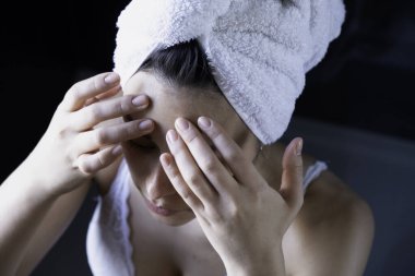 Kafasında havluyla duş aldıktan sonra pencereye bakan çekici bir kadın.