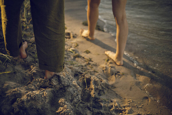 feet on the beach. feet on the sand near water. couple in love by the river.