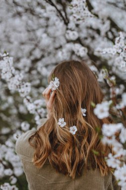 Kız baharda çiçek açan elma ağacının yanında