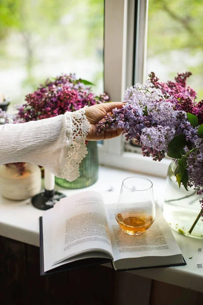 Tangan Seorang Wanita Meraih Untuk Karangan Bunga Lilac Oleh Jendela — Stok Foto