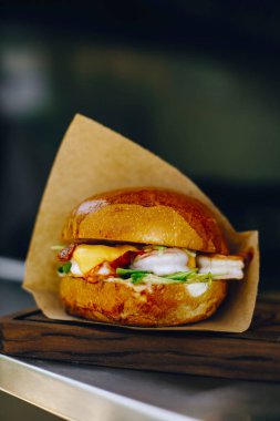 Tahtada kahverengi kağıt içinde sulu bir burger.