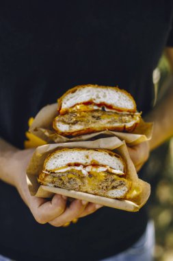 Siyah eldivenli bir adam hamburgeri ikiye böler.
