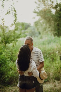 Birbirine aşık çiftler ormanda sarılıp öpüşüyorlar.