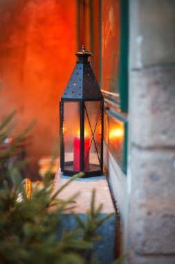 Binanın ön cephesindeki güzel bir şamdanda mum yakmak köknar dallarının arka planında Noel ruhu süslemeleri yapmak.