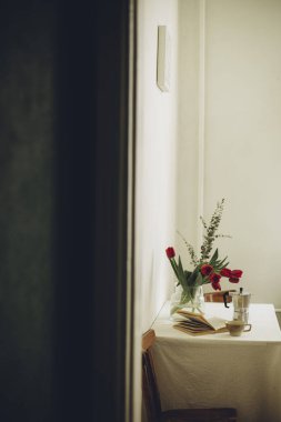 İskandinav tarzı beyaz duvar boyunca mutfak masasındaki bir buket lalenin makro fotoğrafı.