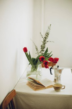 İskandinav tarzı beyaz duvar boyunca mutfak masasındaki bir buket lalenin makro fotoğrafı.