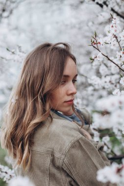 Kız nazikçe bahçeye bakar ya da baharda çiçek açan elma ağacının yanına park eder.