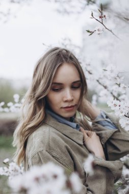 Kız nazikçe bahçeye bakar ya da baharda çiçek açan elma ağacının yanına park eder.