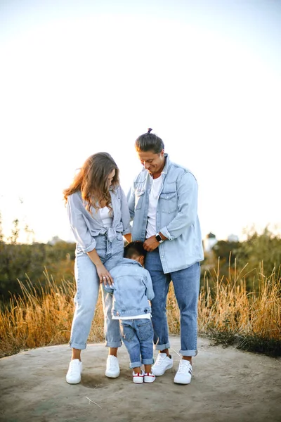 happy family in casual clothes in the park at sunset. the child needs parental protection. young happy family concept. little boy and his parents