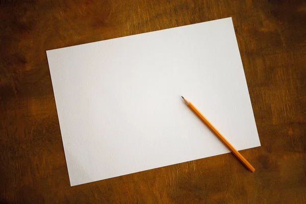 white sheet of paper with a pencil on a wooden surface. copy space and place for text. preparation for drawing. View from above, Education Concept