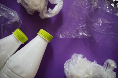Plastik ürünler tarafından çevre kirliliği. Ev atıkları. Mor arka planda plastik şişeler ve paketler.