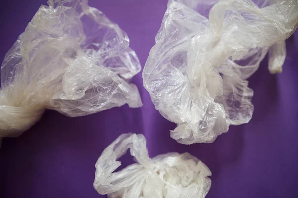 Plastik ile çevre kirliliği. Mor arka planda buruşmuş plastik torbalar..