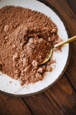 Kakao tozu üstü görünür. Beyaz bir tabakta kakao tozu. Altın kaşığa kakao tozu sürdüm. Kakao pişirme malzemesi