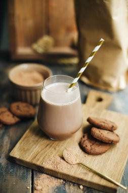 Bir fincan sıcak kakao. Şeffaf bardakta kakao içiyorum. Tahta üzerinde kurabiyeler olan sıcak bir içecek. Çizgili kamışlı sıcak çikolata