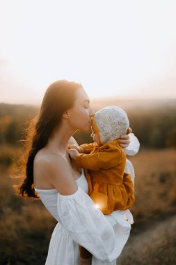 Mutlu anne çocuğunu öper. Genç anne çocuğunun alnından öper. Beyaz elbiseli bir kadın kucağında bir bebek tutuyor. anne sevgisi ve bakımı