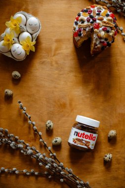 KYIV, UKRAINE - APRIL 1, 2021:jar of nutella top view. Easter cake on a wooden surface with place for text. composition of eggs, pussy willow branches, Easter cake and jars of nutella. copy space cent