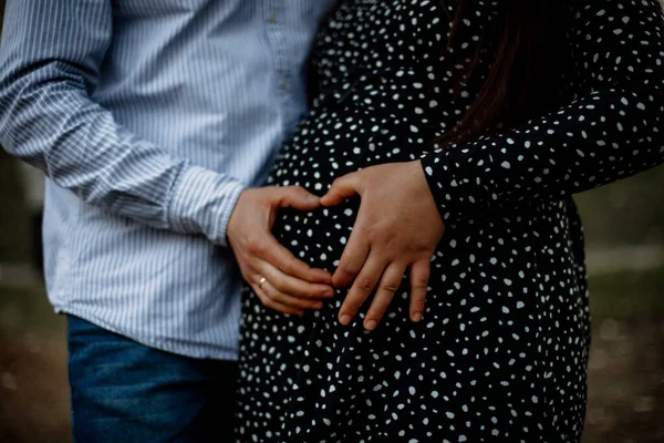 father and mother made a heart on a pregnant belly. couple in love makes a heart out of their hands. hand-made heart on a pregnant tummy.