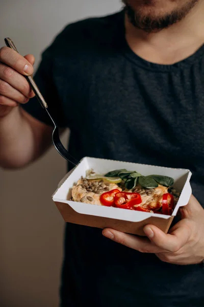 a man is going to eat healthy food in paper packaging. food in paper packaging in hands close-up. healthy food from delivery. concept of a healthy diet for modern young people.
