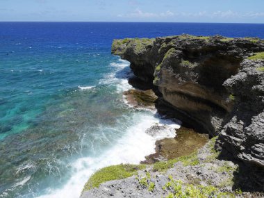 Tropikal bir adada denizin mavi suları üzerinde nefes kesici uçurum ve kaya oluşumu. 