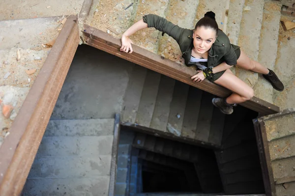 Mädchen in der Nähe der Ziegelmauer im militärischen Stil. Lara Kate Stil. — Stockfoto