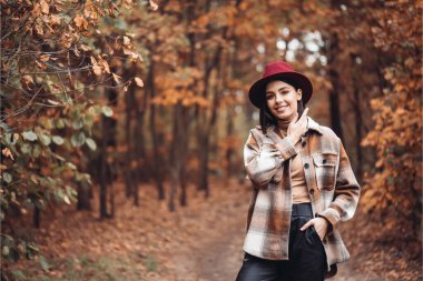 Sonbahar gününde güzel bir kadın. Güzellik ve moda. Sonbahar modası ve yaşam tarzı. Sıcak sonbahar kıyafetleri, şapka ve sarı eşarp giyen güzel bir kadın. Sonbahar havası. Açık havada şık bir kadın..