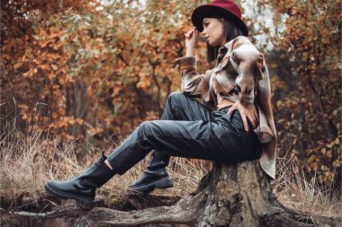 Sonbahar gününde güzel bir kadın. Güzellik ve moda. Sonbahar modası ve yaşam tarzı. Sıcak sonbahar kıyafetleri, şapka ve sarı eşarp giyen güzel bir kadın. Sonbahar havası. Açık havada şık bir kadın..