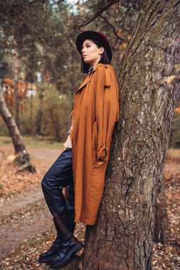 Sonbahar gününde güzel bir kadın. Güzellik ve moda. Sonbahar modası ve yaşam tarzı. Sıcak sonbahar kıyafetleri, şapka ve sarı eşarp giyen güzel bir kadın. Sonbahar havası. Açık havada şık bir kadın..